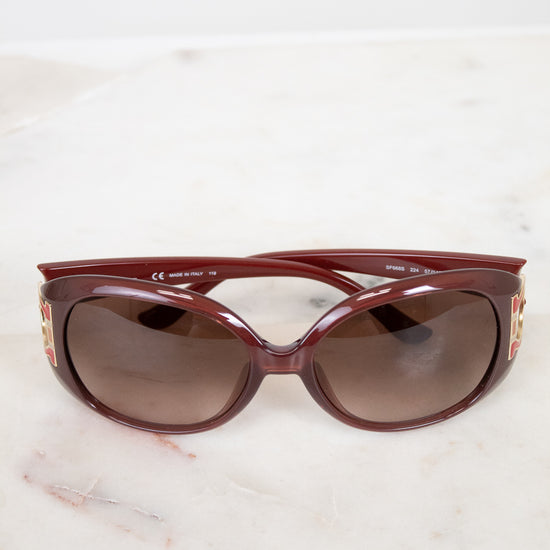 Maroon sunglasses on a light marble surface