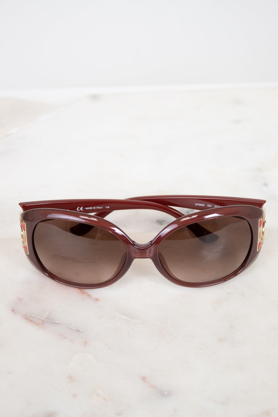 Maroon sunglasses on a light marble surface