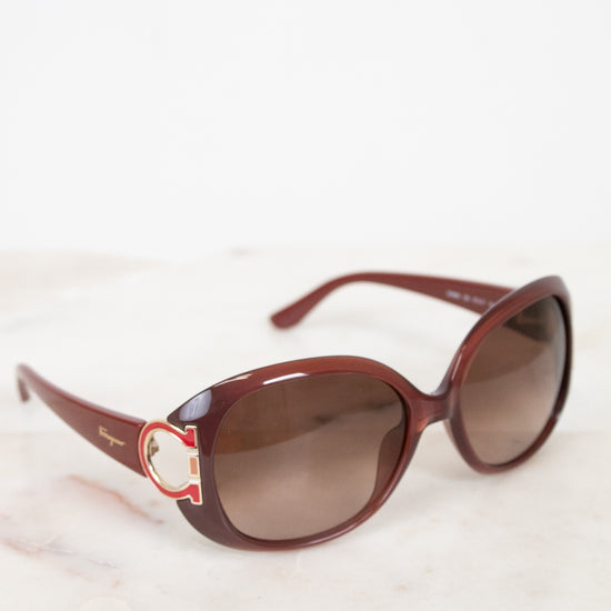 Brown sunglasses with a logo on a light background