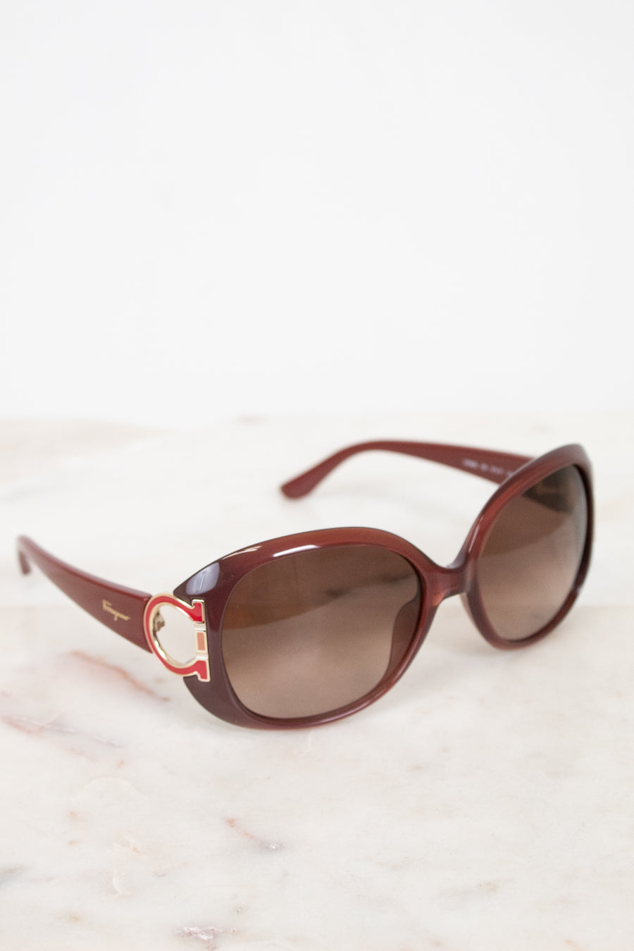 Brown sunglasses with a logo on a light background