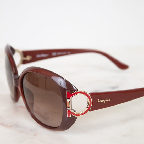 Salvatore Ferragamo sunglasses with brown lenses and red frame on a light background