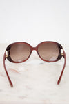 Maroon sunglasses with gradient lenses on a light marble background