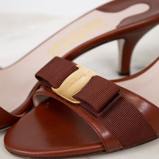 Brown high-heeled shoes with a gold buckle on a marble surface