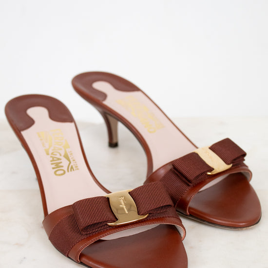 Brown high-heeled shoes with gold accents on a light background