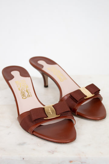 Brown high-heeled shoes with gold accents on a light background