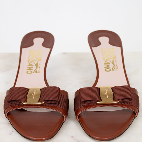 Pair of brown sandals with gold accents on a white marble surface