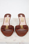 Pair of brown sandals with gold accents on a white marble surface