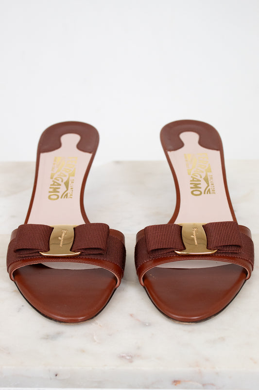 Pair of brown sandals with gold accents on a white marble surface