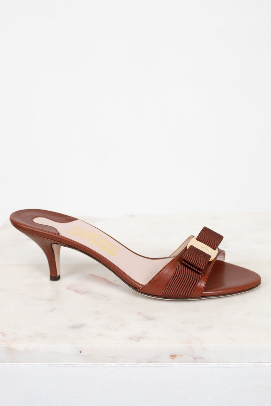 Brown high-heeled sandal with a bow on a white background