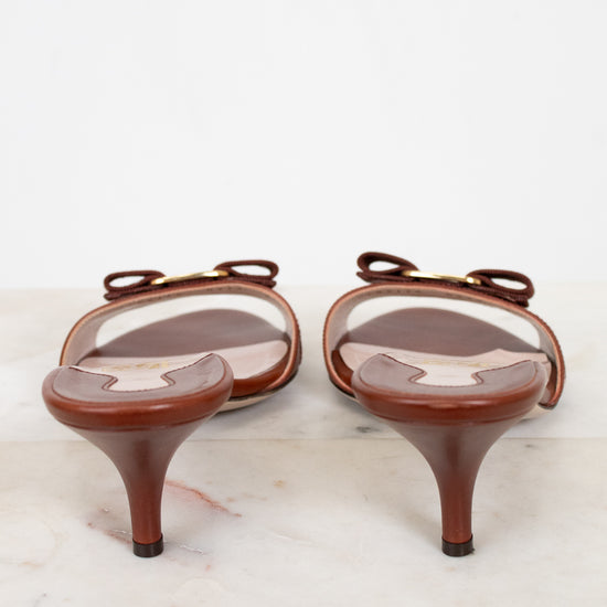 Pair of brown high-heeled shoes with clear covers on a white marble surface