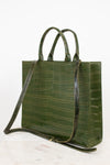 An olive green crocodile-embossed leather tote bag with dual top handles and a detachable shoulder strap, displayed on a light marble surface against a white background.
