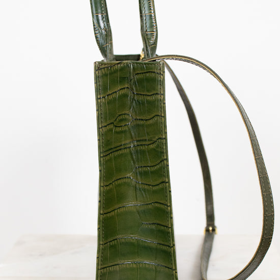 An olive green crocodile-embossed leather shoulder bag with a matching adjustable shoulder strap, shown against a plain white background.