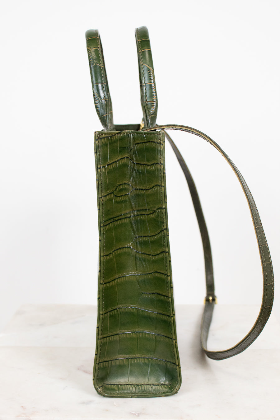 An olive green crocodile-embossed leather shoulder bag with a matching adjustable shoulder strap, shown against a plain white background.