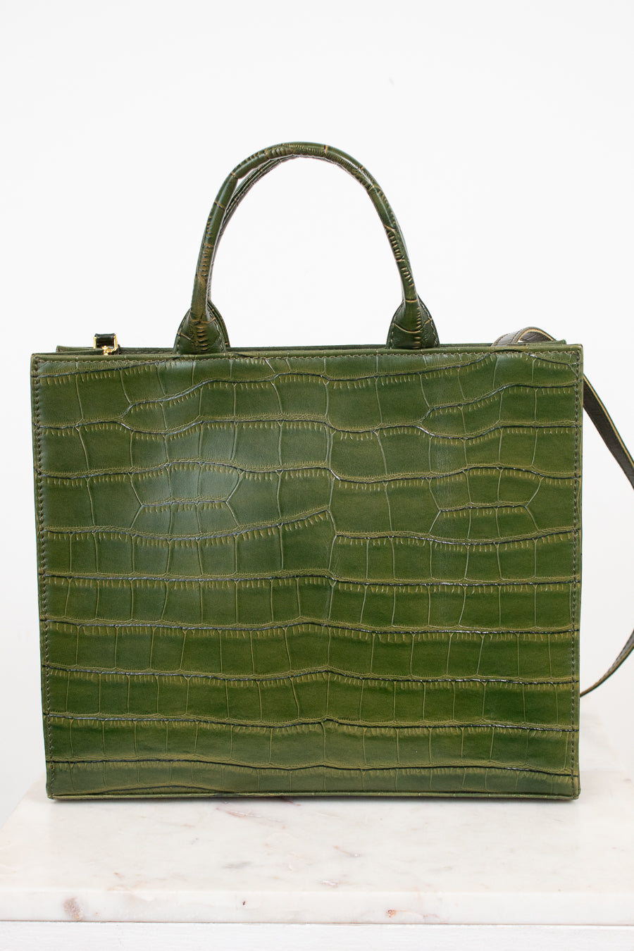 An olive green crocodile-embossed leather handbag with double top handles, displayed on a white marble surface against a white background.