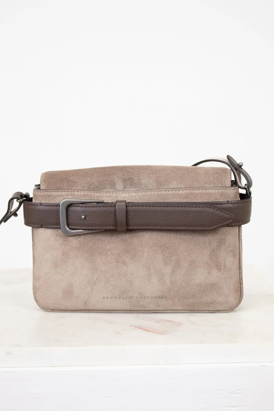 Gray suede handbag with a brown strap on a white background