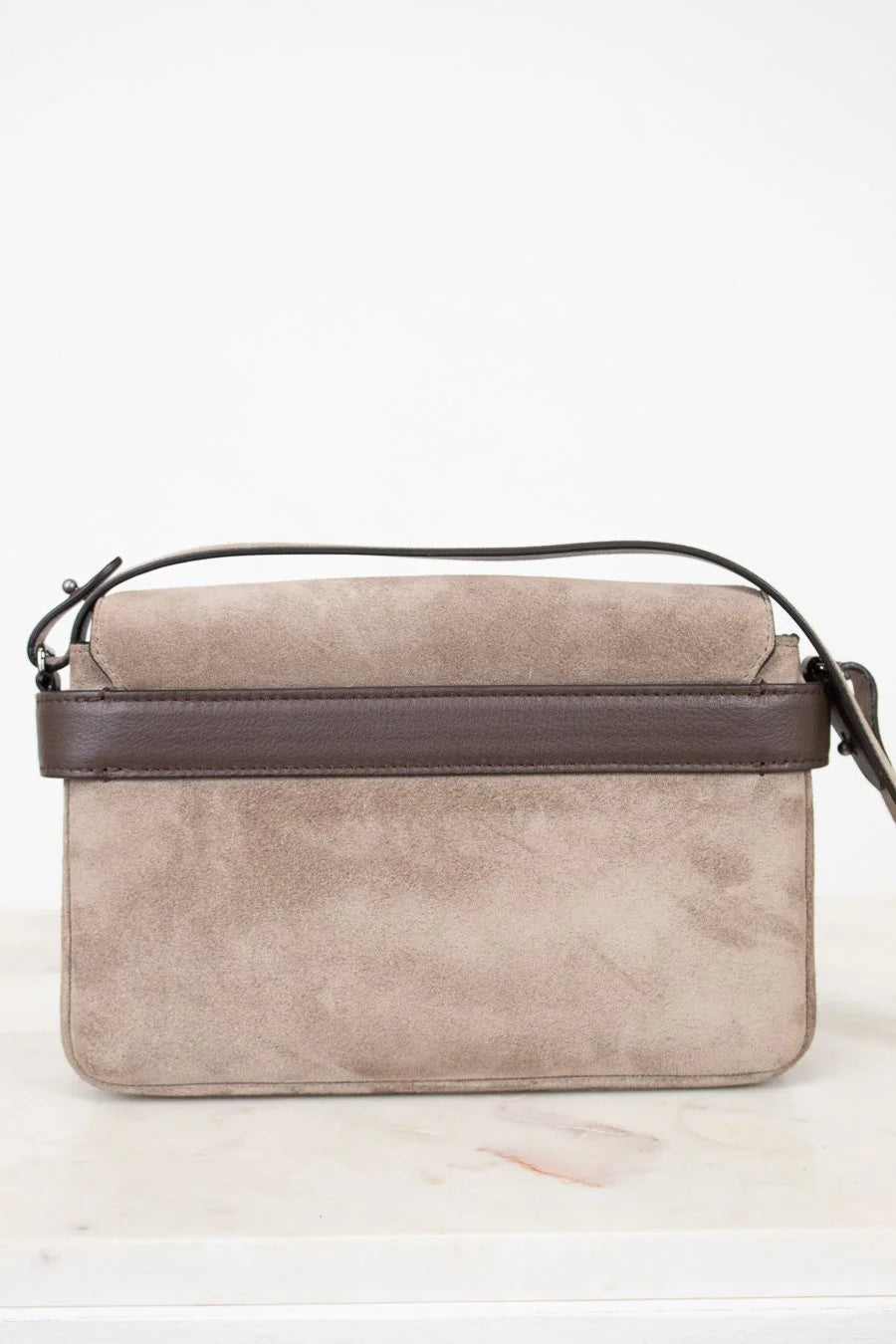 Beige handbag with brown strap on a white background
