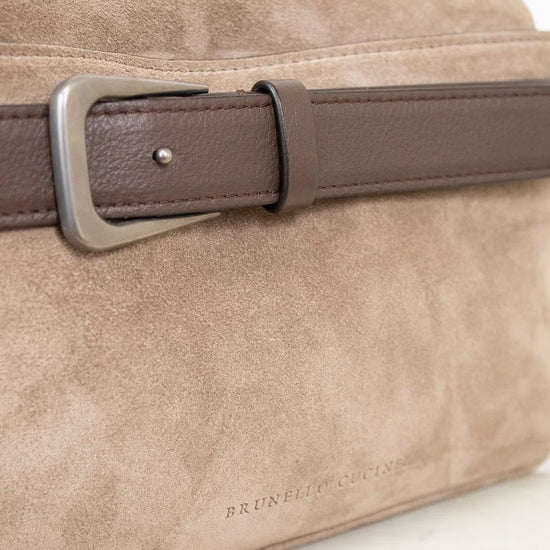 Beige handbag with a brown leather strap on a marble surface