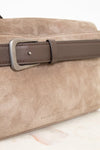 Beige handbag with a brown leather strap on a marble surface