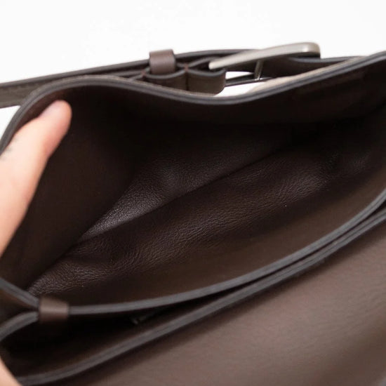 Close-up of a interior brown leather on suede bag with a hand opening it on a white background