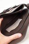 Brown leather interior of bag with a visible brand label held by a hand on a light background
