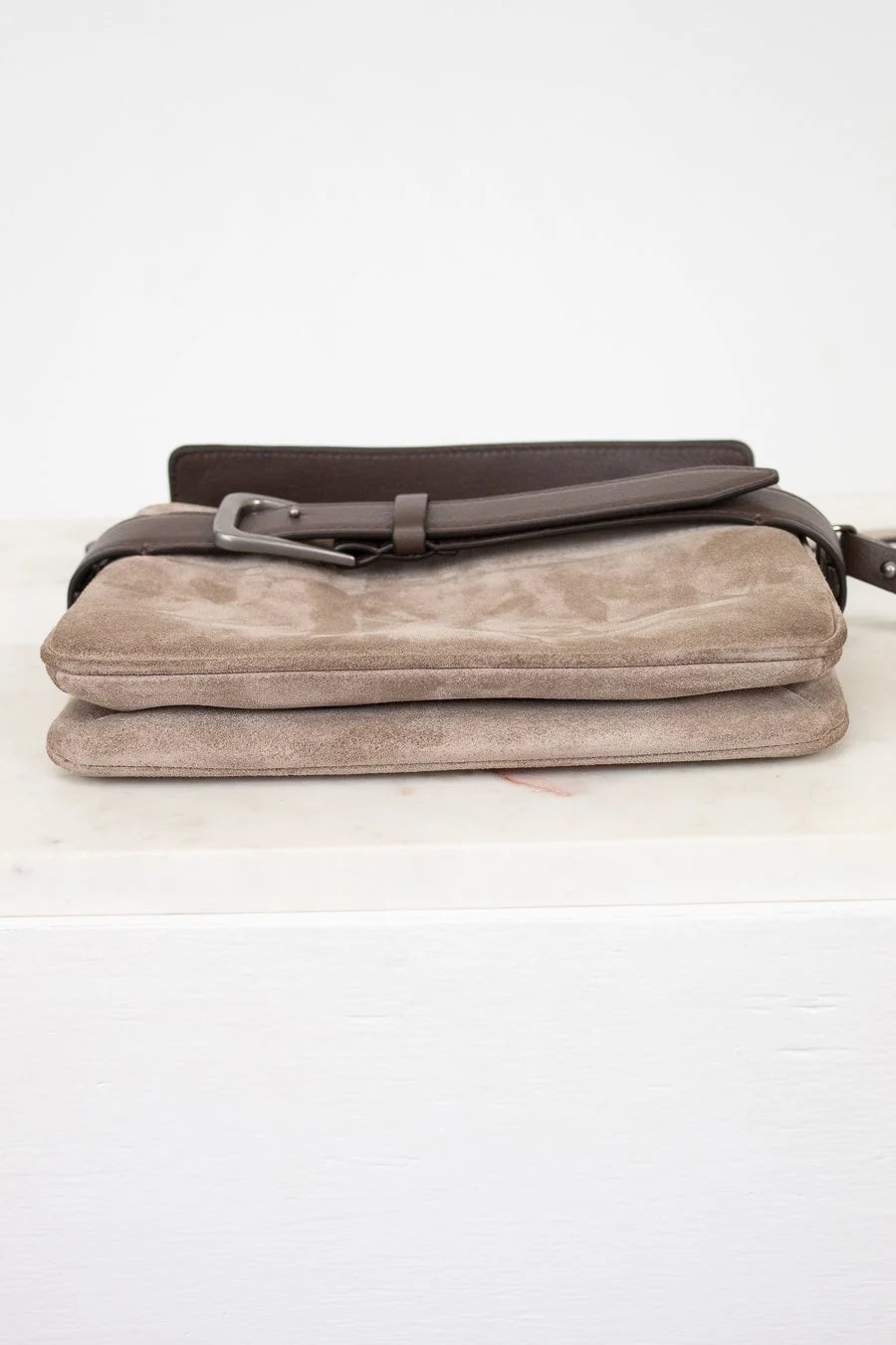 Beige clutch bag with a brown strap on a white background