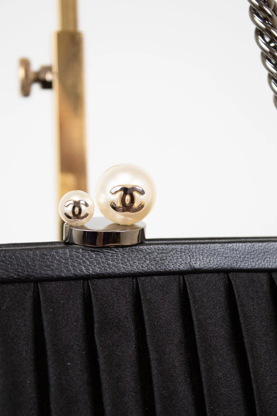 Close-up of a black handbag with Chanel logo on a white background