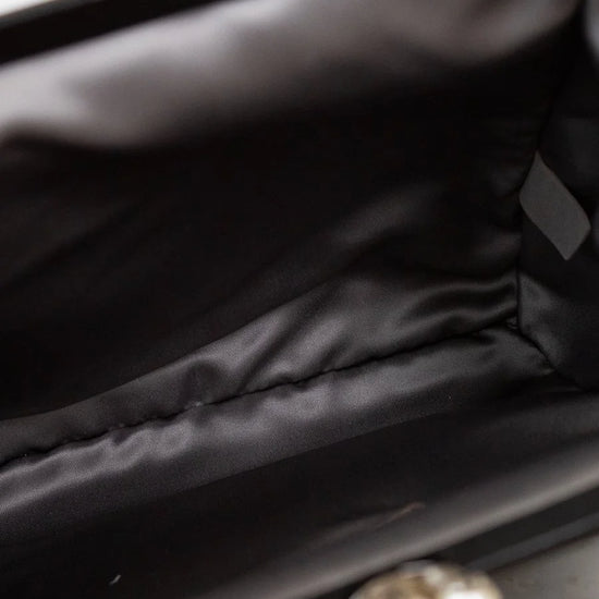 Close-up of interior of a black bag with a blurred pearl in the foreground