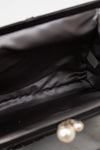 Close-up of interior of a black bag with a blurred pearl in the foreground