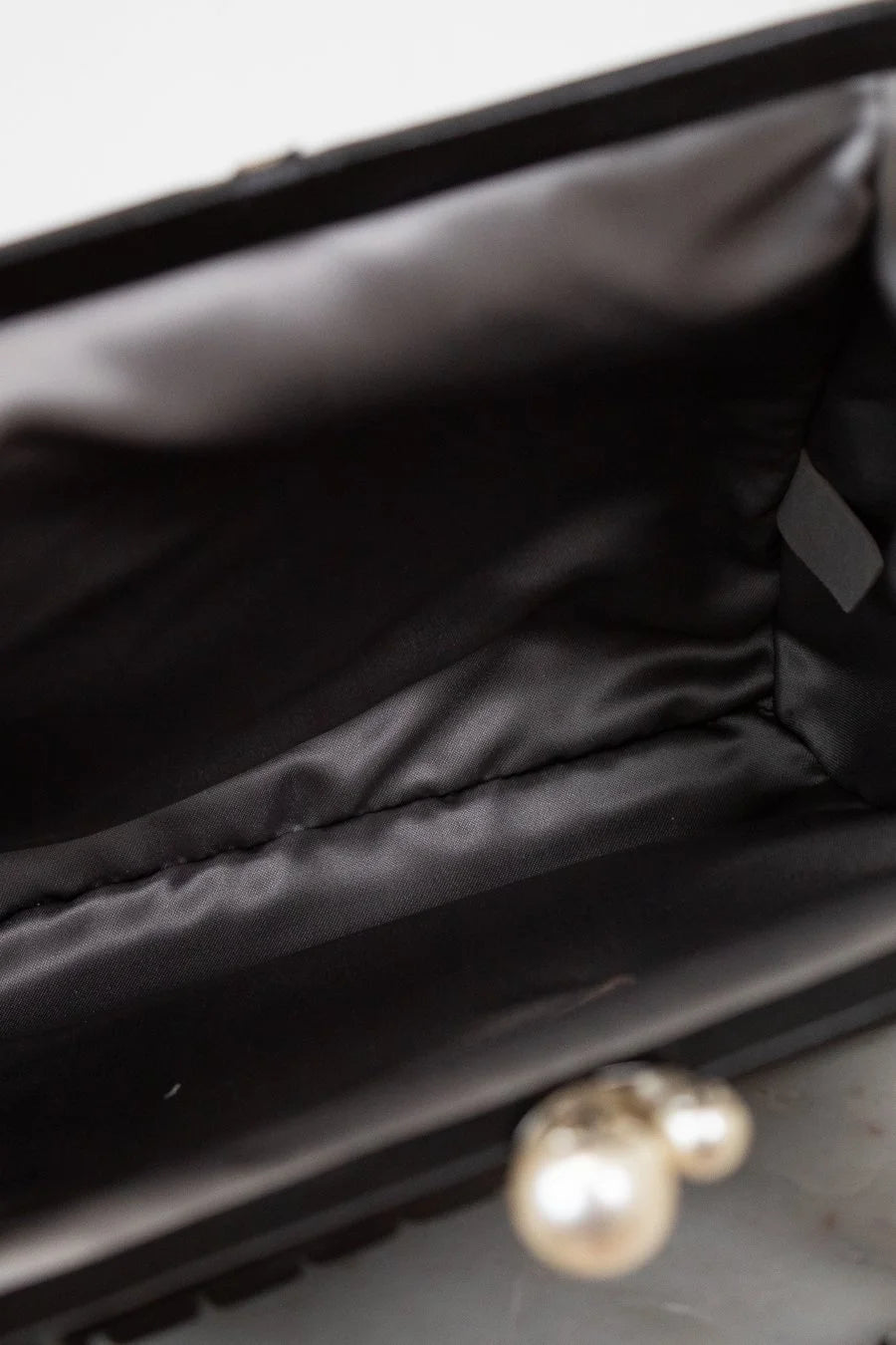 Close-up of interior of a black bag with a blurred pearl in the foreground