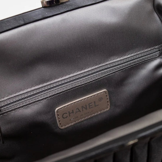 Close-up of a Chanel handbag with a silver/pearl clasp on a light gray background
