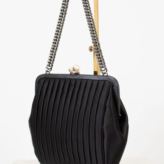 Black pleated handbag with chain strap on a white background