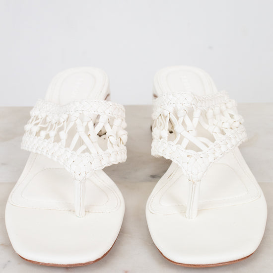 Pair of white sandals with lace details on a marble surface