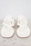 Pair of white sandals with lace details on a marble surface