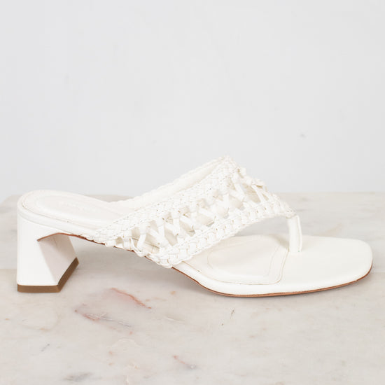 White sandal with crochet like details on a marble surface