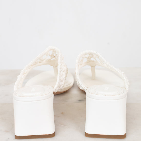 White block heeled sandals on a marble surface