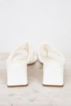 White block heeled sandals on a marble surface