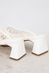 White high-heeled shoes with a textured strap on a light gray background