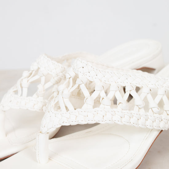 White sandal with crochet detailing on a light gray background