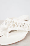 White sandal with crochet detailing on a light gray background