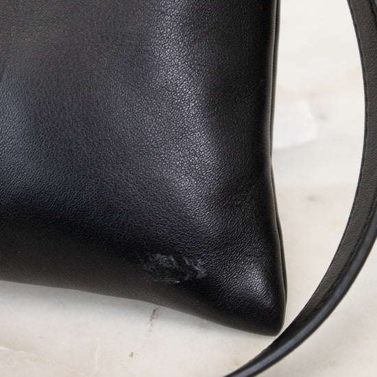 Black leather handbag with a strap on a light background