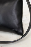 Black leather handbag with a strap on a light background