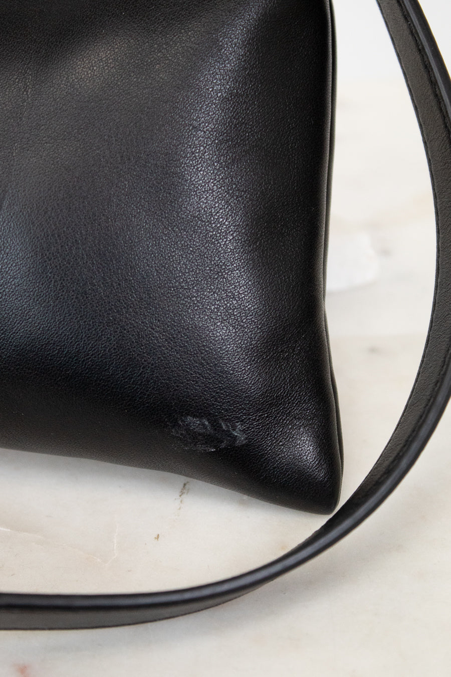 Black leather handbag with a strap on a light background