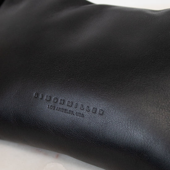 Black leather bag with 'Simon Miller' branding on a marble surface
