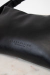 Black leather bag with 'Simon Miller' branding on a marble surface