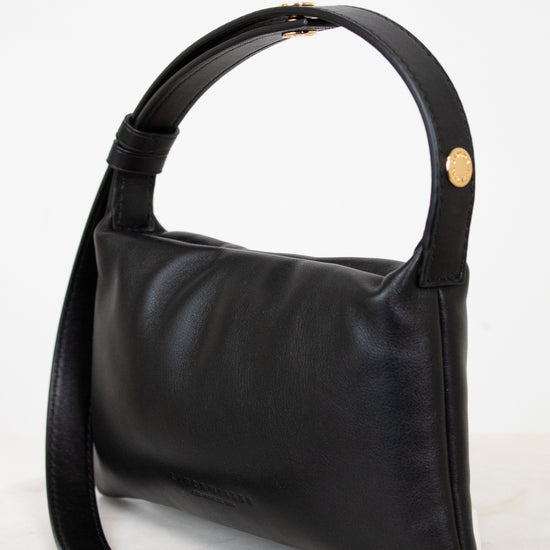 Black handbag with a gold snap on a light gray background