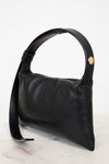 Black handbag with a gold snap on a light gray background