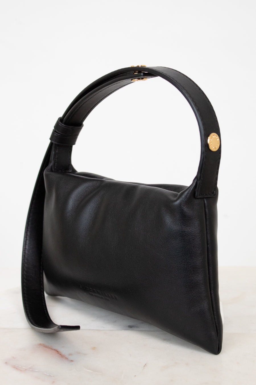 Black handbag with a gold snap on a light gray background