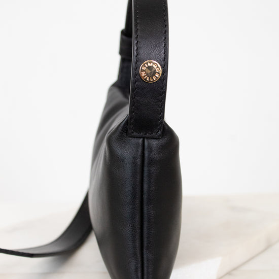 Black leather bag with a gold snap on a white marble surface