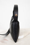 Black leather bag with a gold snap on a white marble surface