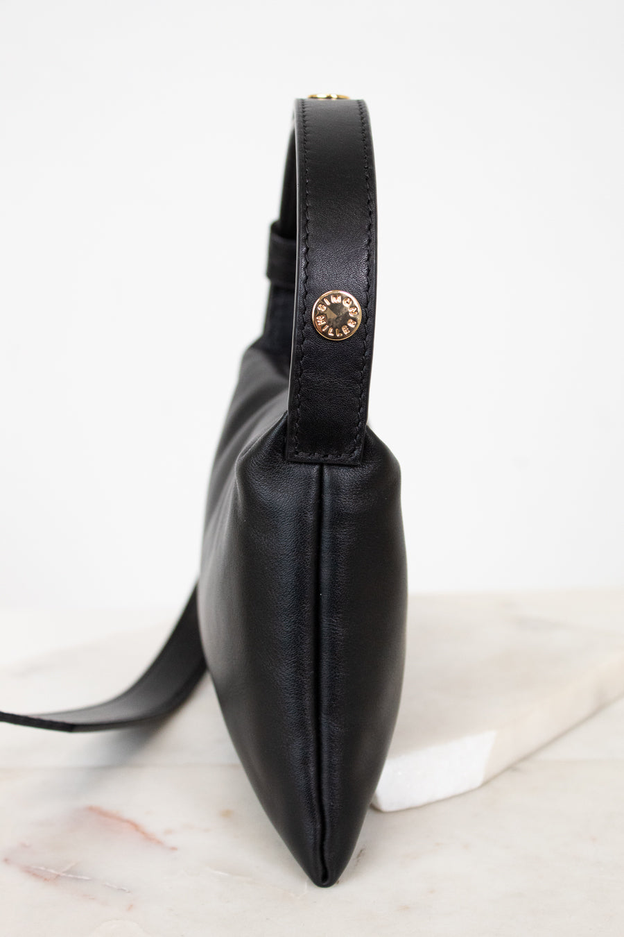 Black leather bag with a gold snap on a white marble surface